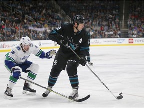 Vancouver Canucks' Tim Schaller (59) fights for the puck against San Jose Sharks' Joe Thornton (19), who passed the puck to Sharks' Erik Karlsson (65), who scored during the third period of an NHL hockey game in San Jose, Calif., Friday, Nov. 23, 2018.