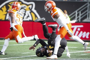 Hamilton Tiger-Cats quarterback Jeremiah Masoli (8) is upended after a throw by B.C. Lions defensive back T.J. Lee (6) and BC Lions linebacker Jordan Herdman (53) during first half CFL Football division semifinal game action in Hamilton, Ont. on Sunday, November 11, 2018.