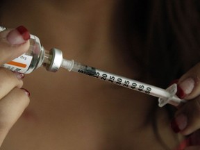 A woman fills a syringe as she prepares to self-administer insulin.