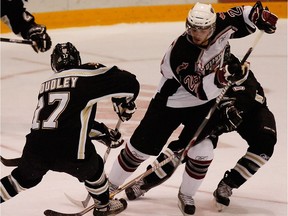 Former Vancouver Giants' star Michal Repik tries to avoid the tag-team checking of Chilliwack Bruins' Michael Proudley, left, and Cody Hobbs.