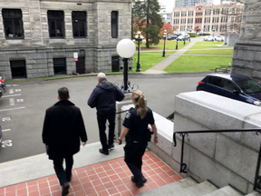 Two key officials at British Columbia's legislature were placed on indefinite leave today and were escorted out of the building by security officials. B.C. legislature Sergeant-at-Arms Gary Lenz, centre, is escorted out of the legislature by security, in Victoria on Tuesday, Nov. 20, 2018.