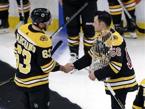 Boston Red Sox pitcher Joe Kelly, holding the Commissioner's Trophy that goes to the World Series champions, shakes hands with Boston Bruins left-winger Brad Marchand prior to the Bruins' game against the visiting Dallas Stars on Monday, Nov. 5, 2018.