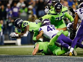 Chris Carson of the Seattle Seahawks dives passed Ben Gedeon of the Minnesota Vikings for a touchdown in the fourth quarter at CenturyLink Field on December 10, 2018 in Seattle, Washington.