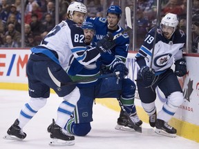 Vancouver Canucks defenseman Erik Gudbranson (44) fights for control of the puck with Winnipeg Jets center Mason Appleton (82) and Winnipeg Jets left wing Nic Petan (19) during first period NHL action at Rogers Arena in Vancouver, Saturday, Dec. 22, 2018.