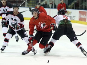 Team Canada's Alex Formenton splits two U Sports defenders during Wednesday's exhibition game at the Q Centre in Colwood.