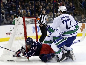 Columbus Blue Jackets forward Josh Anderson, left, collides with the goal in front of Vancouver Canucks goalie Jacob Markstrom and defenseman Ben Hutton during the second period.