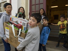 Grade 7 students Christopher Shuen (left) Dana Edamura (centre) and Helen Mihlar (right) get help from kindergarten students Ellie McQueen (left) Herschel Sharma (centre) and Sebastian Gonzalez (right) as they carry items destined for the Empty Stocking Fund fundraiser at Kerrisdale Elementary in Vancouver Thursday.