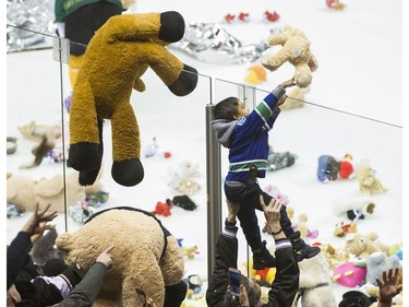 A young fan gets a helping hand as teddy bears and other stuffed animals are tossed on the ice during the annual Teddy Bear Toss! after the Vancouver Giants score on the Victoria Royals in a regular season WHL hockey game at the Pacific Coliseum, Vancouver,  December 08 2018.