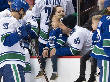 Antoine Roussel #26 of the Vancouver Canucks shares a laugh with teammate Sam Gagner #89 and his son Cooper during the Vancouver Canucks Super Skills Contest at Rogers Arena in Vancouver, BC, December, 2, 2018.