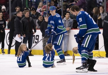 Elias Pettersson #40 of the Vancouver Canucks pulls Blanca (left) and Elle Eriksson around the ice while Loui Eriksson #21 of the Vancouver Canucks entertains Lola after the Vancouver Canucks Super Skills Contest at Rogers Arena in Vancouver, BC, December, 2, 2018.