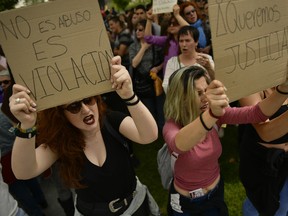 Two women shout slogans as they hold up signs reading,''it is not a sexual abuse. It's a rape'" and "We want Justice'' during a protest in front of the Regional Court in Pamplona, northern Spain, Friday, April 27, 2018.