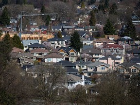 A condo building is seen under construction surrounded by houses in Vancouver, B.C., on March 30, 2018. The Real Estate Board of Greater Vancouver says prices for detached homes, townhouses and condos have fallen for two consecutive months.