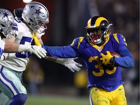 L.A. Rams running back C.J. Anderson stiff arms Leighton Vander Esch of the Dallas Cowboys in the second half in the NFC Divisional Playoff game at Los Angeles Memorial Coliseum on Saturday.