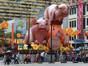 People walk past figurines of the pig ushering for the upcoming Chinese Lunar New Year along the roadside of the Chinatown in Singapore on January 9, 2019.