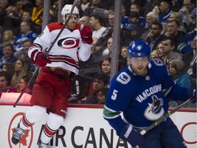 Canucks defenceman Derrick Pouliot skates past as Carolina Hurricane Dougie Hamilton jumps against the boards after scoring in the second period.