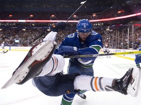 Vancouver Canucks defenceman Derrick Pouliot (5) knocks Edmonton Oilers centre Ryan Nugent-Hopkins (93) to the ice during the first period.