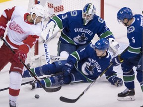 Vancouver Canucks centre Elias Pettersson (40) and defenceman Derrick Pouliot (5) help stop Detroit Red Wings centre Andreas Athanasiou (72) from getting a shot on Canucks goalie Jacob Markstrom (25) during NHL action in Vancouver on Jan. 20.