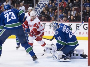 Alex Edler looks on as Detroit Red Wings centre Dylan Larkin tries to get a shot on Canucks goaltender Jacob Markstrom during the first period on Sunday.