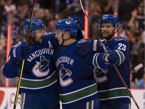 Jake Virtanen, centre, is congratulated by Canucks teammates Chris Tanev, left, and Alex Edler after scoring a goal against the St. Louis Blues last month at Rogers Arena in Vancouver.