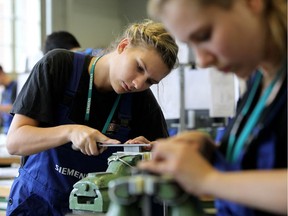 Female mechanical engineering trainees learn the basics of precision filing at the Siemens training center in Berlin, Germany.