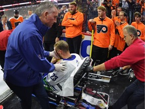 Alex Edler is helped off the ice after suffering a third-period injury Monday.