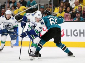 Bo Horvat of the Vancouver Canucks is tripped by Erik Karlsson of the San Jose Sharks at SAP Center in the first period Saturday.