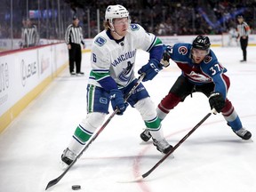 Brock Boeser of the Vancouver Canucks looks for an opening while J.T. Compher of the Colorado Avalanche defends during their Feb. 27, 2019 NHL game in Denver, Colo.