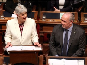 Premier John Horgan looks on as Finance Minister Carole James delivers the budget speech at the legislature in Victoria, B.C., on Tuesday, February 19, 2018.