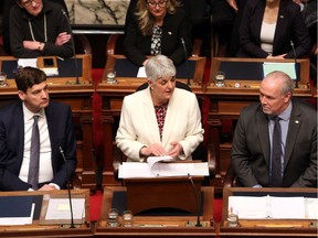 Attorney General David Eby, left and Premier John Horgan look on as Finance Minister Carole James delivers the budget speech at the legislature in Victoria, B.C., on Tuesday, February 19, 2018.