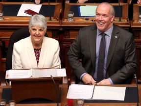 Finance Minister Carole James and Premier John Horgan smile before delivering the budget speech at the legislature in Victoria on Feb. 19, 2019, which has added hundreds of dollars of additional government taxes and fees to the average B.C. family's annual costs.