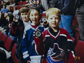 A detail from the old family photo of Braedon Arcand, Brayden Low and Troy Stecher showing off the pucks they were given at a Jan. 2002 Canucks game.