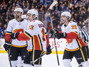 Calgary Flames' Mark Giordano, from left to right, Johnny Gaudreau and Elias Lindholm, of Sweden, celebrate Lindholm's goal during first period NHL hockey action against the Vancouver Canucks, in Vancouver on Saturday, Feb. 9, 2019.