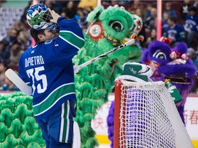 Chinese dancers leave the ice as Vancouver Canucks goalie Michael DiPietro puts on his mask.