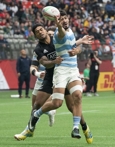 German Schulz of Argentina (in blue and white hoops jersey) loses control of the ball after getting tackled by Regan Ware of New Zealand during rugby sevens action on Day 2 of the HSBC Canada Sevens at BC Place on Sunday, March 10, 2019 in Vancouver.