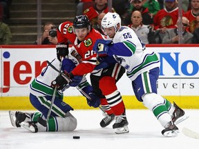 Brandon Saad of the Blackhawks can't shake the "dogged" determination of Vancouver Canucks' defenders Alex (The Bulldog) Biega and Jay Beagle, left, during Monday's NHL game in Chicago.