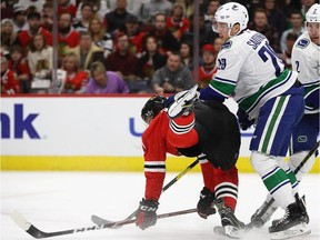 Dylan Strome of the Chicago Blackhawks is dumped to the ice by Ashton Sautner of the Vancouver Canucks at the United Center on March 18, 2019 in Chicago, Illinois.