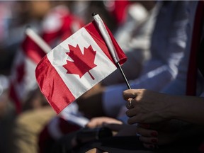 A recent immigrant holds a flag during a Canadian citizenship ceremony.