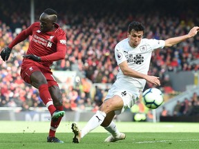 Liverpool striker Sadio Mane (left) takes a shot past Burnley midfielder Jack Cork, which is deflected during the English Premier League soccer match at Anfield in Liverpool, England, on Sunday March 10, 2019.