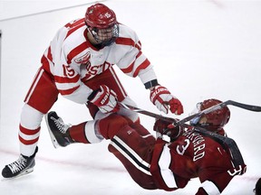Harvard defenseman Jack Rathbone, right, is checked to the ice by Boston University forward Shane Bowers, left, during the third period of the consolation game of the NCAA hockey Beanpot tournament in Boston, Monday, Feb. 11, 2019.