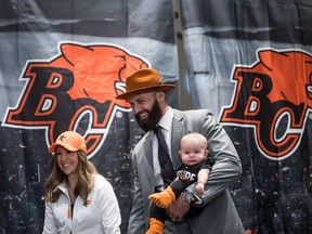 New B.C. quarterback Mike Reilly carries his six-month-old daughter Cadence as he and his wife Emily arrive for a Lions news conference in Surrey on Feb. 12.