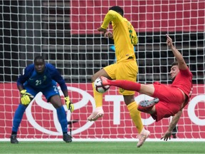 Canada's Jay Chapman, right, has his shot attempt blocked by French Guiana's Alain Moges, centre, as goalkeeper Jean-Beaunel Petit-Homme, back left, watches during the first half.