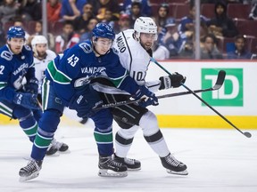 Quinn Hughes of the Vancouver Canucks wrestles for position with Los Angeles Kings' Michael Amadio during Thursday's NHL game in Vancouver.
