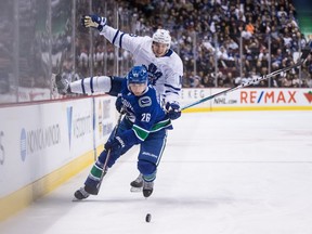 Toronto Maple Leafs' Mitchell Marner, back, jumps to avoid a collision with Vancouver Canucks' Antoine Roussel, of France, during the third period.