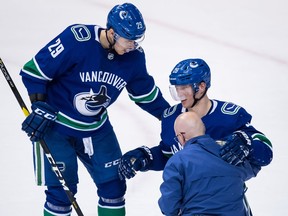 Vancouver Canucks' Antoine Roussel, right, is helped up by teammate Ashton Sautner and a trainer after being injured during Wednesday's NHL game in Vancouver. Roussel is done for the season.