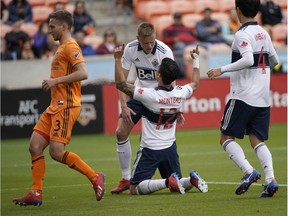 Vancouver Whitecaps's Fredy Montero (12) celebrates with Andy Rose, rear, after scoring on a penalty kick as Houston Dynamo's Adam Lundqvist (3) runs past during the first half of an MLS soccer match Saturday, March 16, 2019, in Houston.
