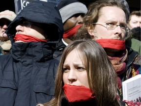 Muzzled protesters from a coalition of human rights groups listen to fellow demonstrators Thursday March 5, 2009 outside the Montreal courthouse urging Quebec's justice minister to ban SLAPPs — strategic lawsuits against public participation, in which large corporations sue their critics to intimidate them. (POSTMEDIA FILES)