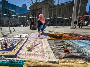 Samira lays a rose on a blanket as people gather in front of Vancouver Art Gallery in support of those who died and were affected by the shootings in New Zealand.