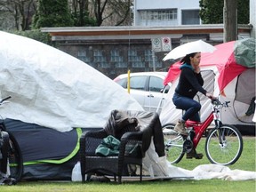 man stands by his tent as Vancouver Police and Fire crews check for safety violations at the homeless camp in Oppenheimer Park.