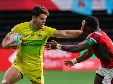 Australia's Simon Kennewell stiff arms Kenya's Mike Agevi during World Rugby Sevens Series action in Vancouve on Sunday, March 10, 2019.