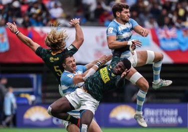 South Africa's Werner Kok (left, in green) and Sakoyisa Makata (also in green) jump for the ball against Argentina's Renzo Barbier (left, in blue and white hoops) and Francisco Ulloa (far right) during World Rugby Sevens Series action in Vancouver on Sunday, March 10, 2019.